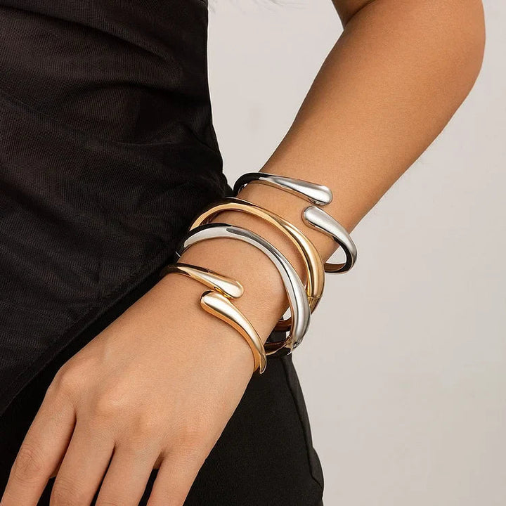 Frau mit stilvollen goldenen und silbernen Armreifen, modernes Schmuckdesign, Modeaccessoire.