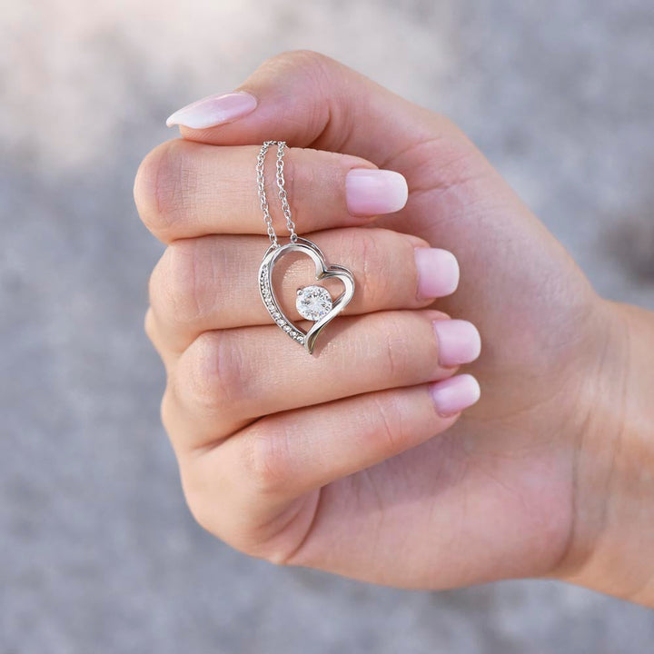 Hand hält silberne Herz-Halskette mit Diamant, Schmuck, Geschenk, elegantes Design.