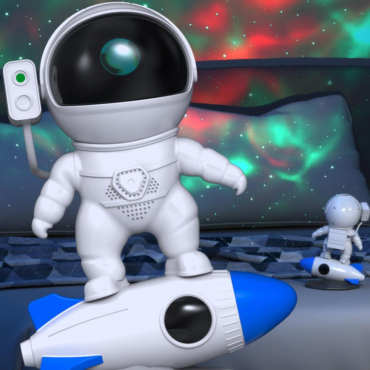 Astronaut-Spielzeugfigur auf blauem Raketen-Spielzeug vor buntem Hintergrund.