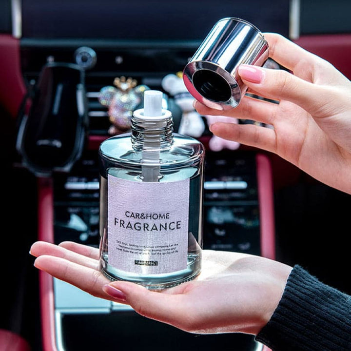 Frau hält Auto- und Raumduftflasche, silberner Deckel, transparentes Glas, im Auto.
