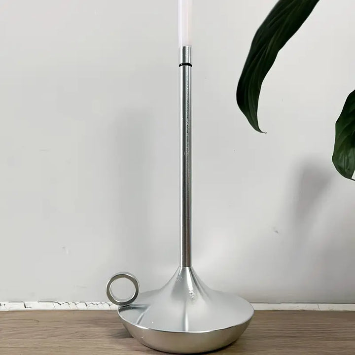 Silberner Kerzenhalter aus Metall mit modernem Design auf Holzoberfläche, minimalistisch.