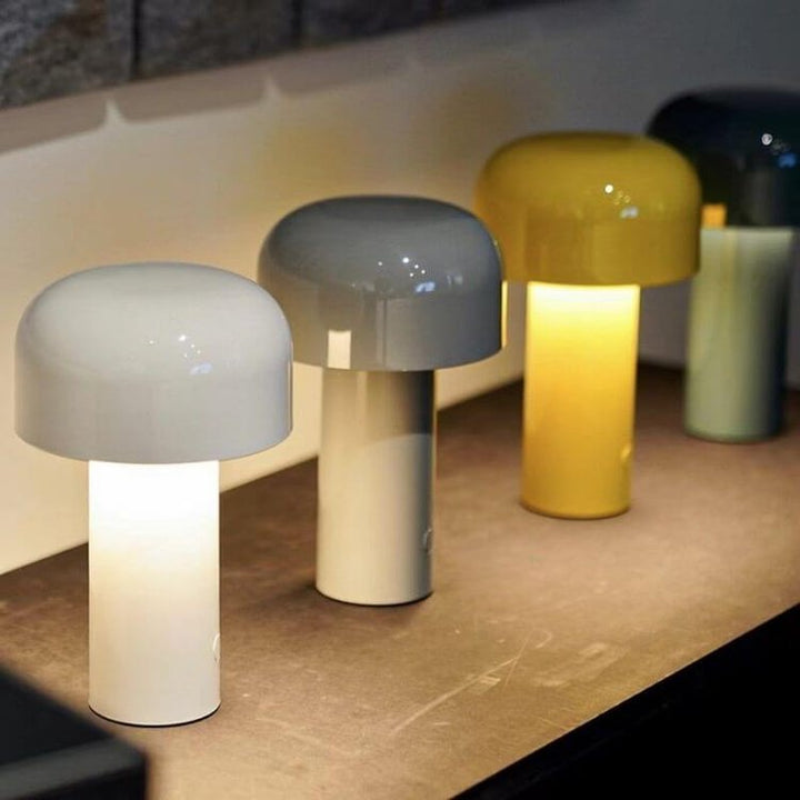 Vier bunte, moderne Tischlampen aus Keramik auf Holzoberfläche, ideal für stilvolle Beleuchtung.