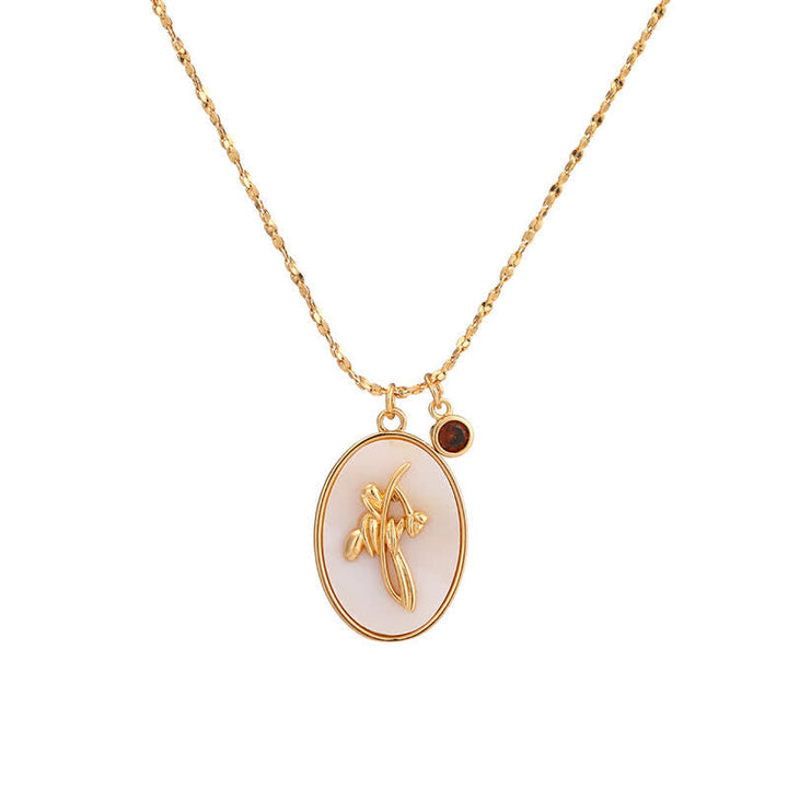 Goldene Halskette mit ovalem Anhänger, Blumenmotiv, weißer Hintergrund, eleganter Schmuck.