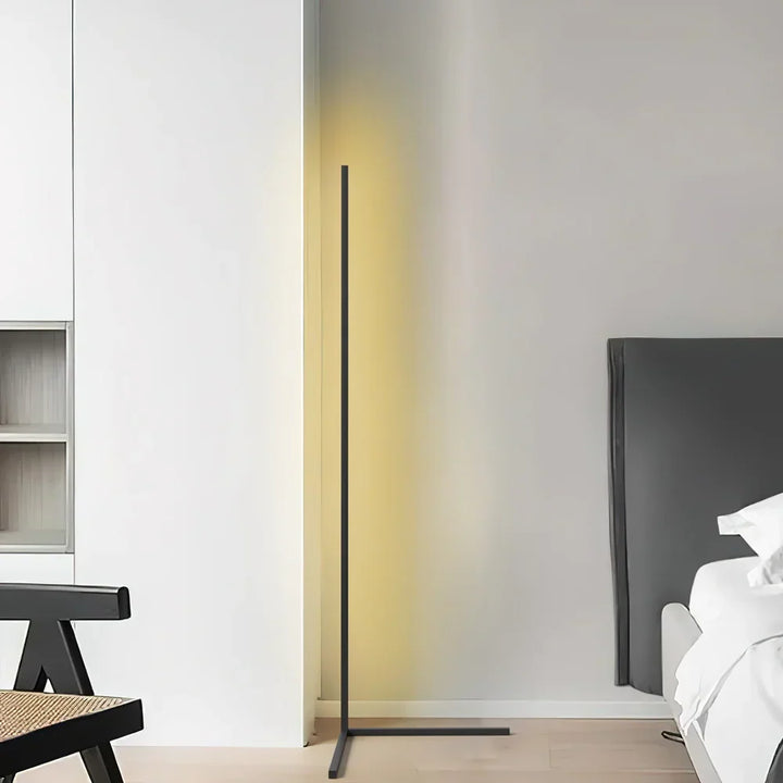 Černá lampa se žlutavým světlem v bílém interiéru, vedle židle a čela postele 7