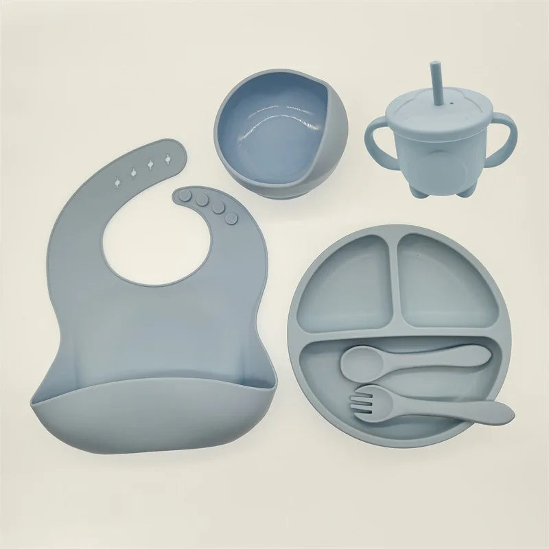 Baby Geschirr Set aus Silikon in Blau, bestehend aus Lätzchen, Teller, Schüssel und Trinkbecher.
