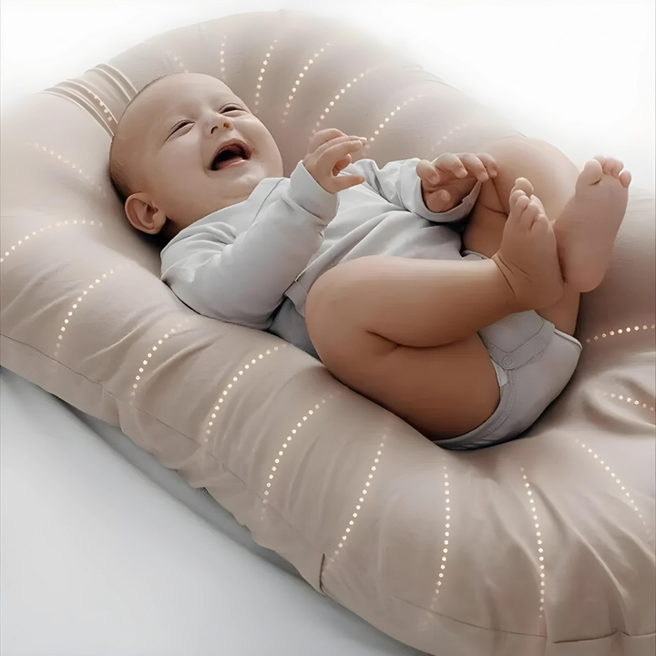 Lachendes Baby auf beigem Babynest, weiche Baumwolle, ideal für Neugeborene, gemütlich und sicher.