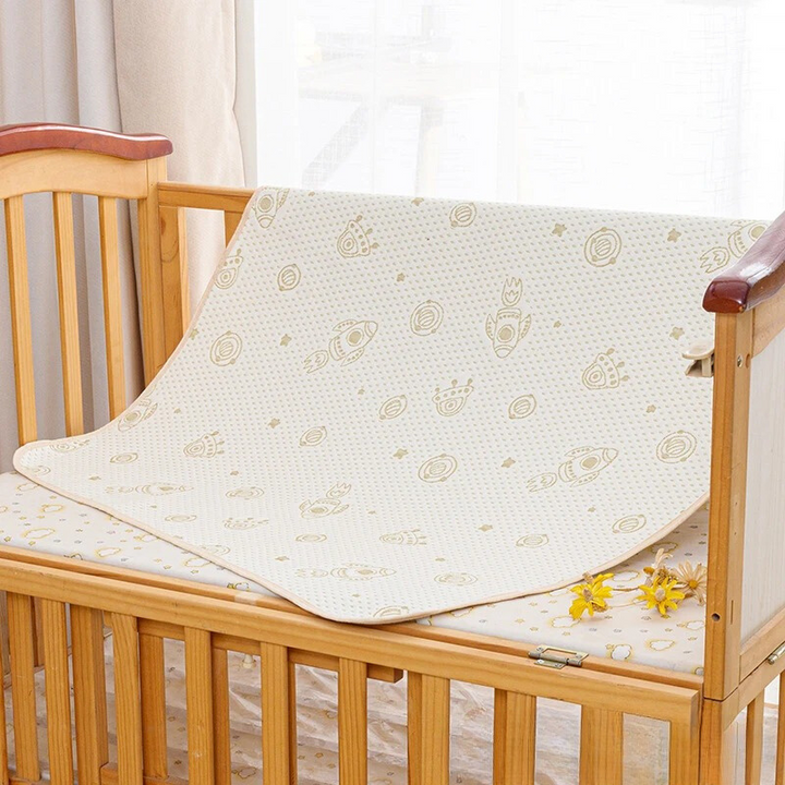 Holz-Kinderbett mit beiger Babydecke, Raketenmuster, Kinderzimmer-Dekor, Tageslicht.