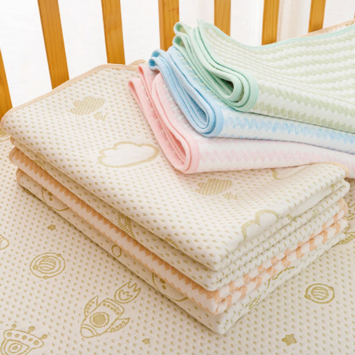 Stapel bunter Babydecken aus Baumwolle mit Mustern auf Holzgitterbett.