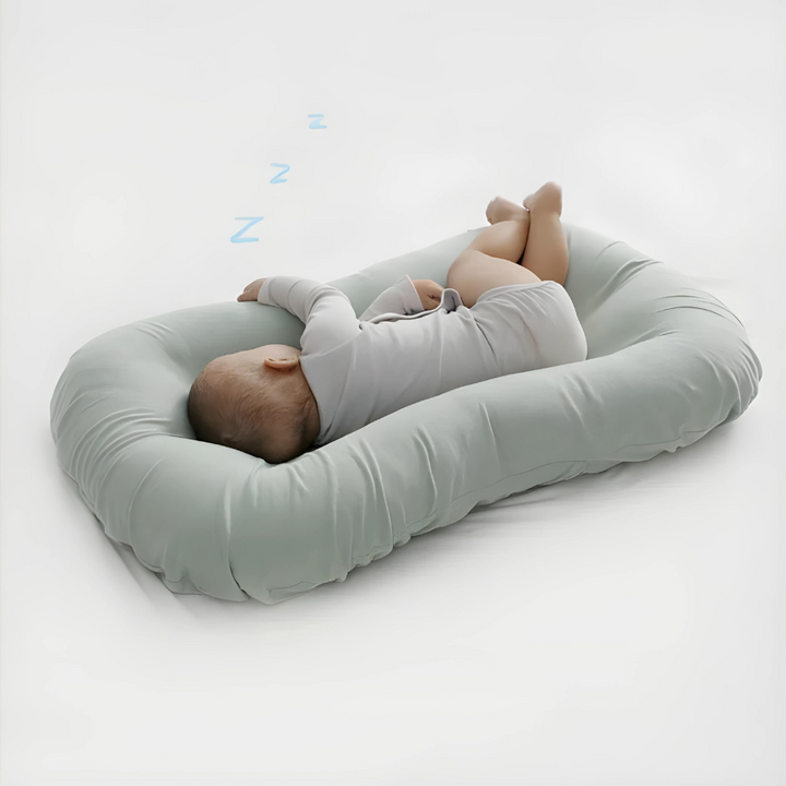 Baby schläft auf hellgrünem Babynest, bequemes Schlafkissen, Neugeborenenbett, weich.