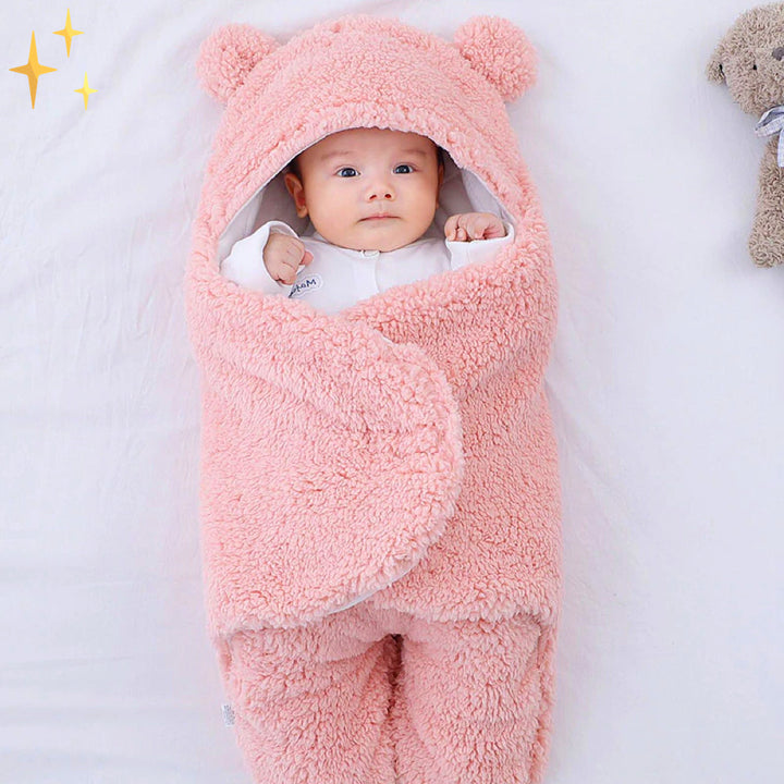 Baby in rosa Plüsch-Babyschlafsack mit Kapuze und Ohren, weich und warm, ideal für Neugeborene.