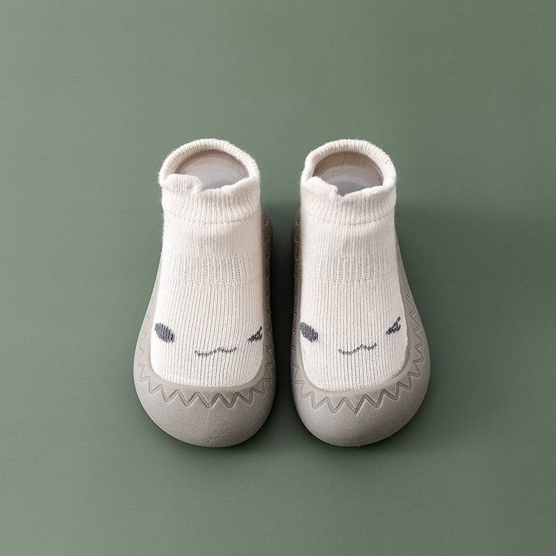 Beige Babyschuhe mit Gesichtsmotiv, rutschfest, weiche Sohle, ideal für Kleinkinder.