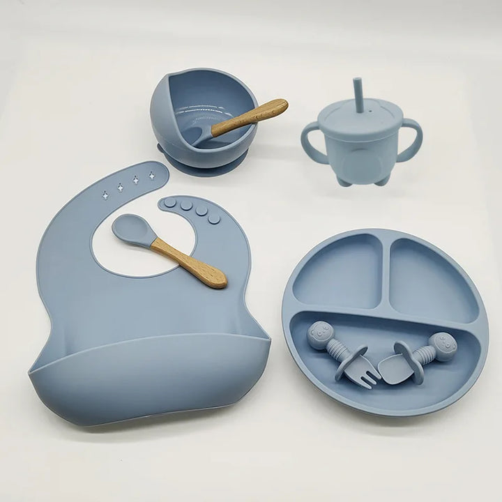 Blaues Silikon-Babygeschirr-Set mit Lätzchen, Teller, Schüssel, Becher und Besteck.