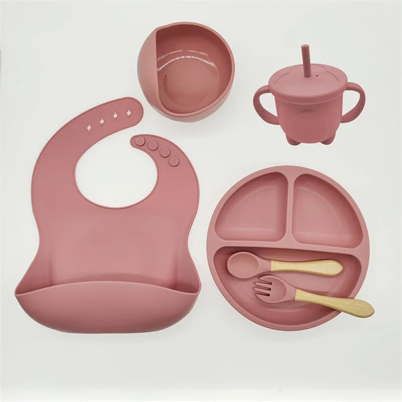 Rosa Silikon-Babyteller-Set mit Lätzchen, Becher, Schüssel, Löffel und Gabel, BPA-frei.