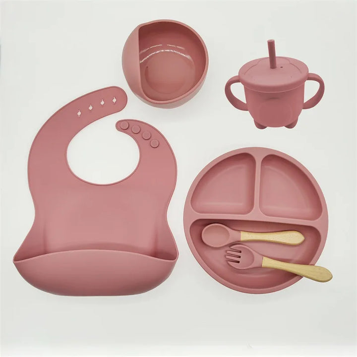 Rosa Silikon-Babyteller-Set mit Lätzchen, Becher, Schüssel, Löffel und Gabel, BPA-frei.