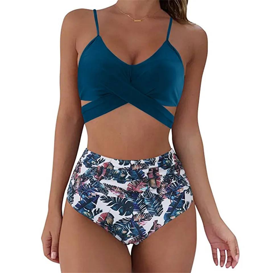 Frau in blauem Bikini-Top und tropisch gemusterter High-Waist-Badehose.