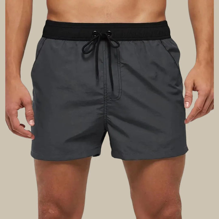 Graue Herren-Badeshorts mit schwarzem Bund und Kordelzug, ideal für Sommer und Strand.