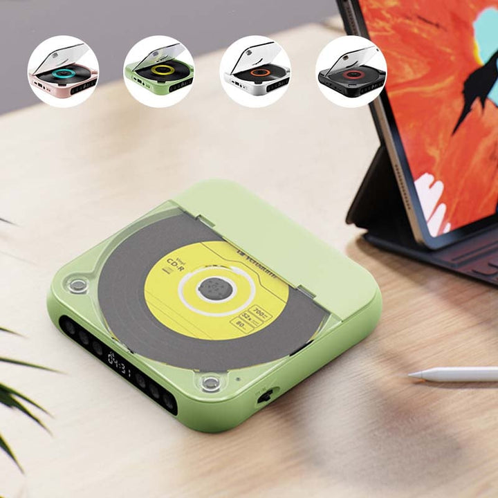 Zelený přehrávač s uzavřeným víkem na stole vedle tabletu, nahoře čtyři barevné varianty v kolečkách. 6