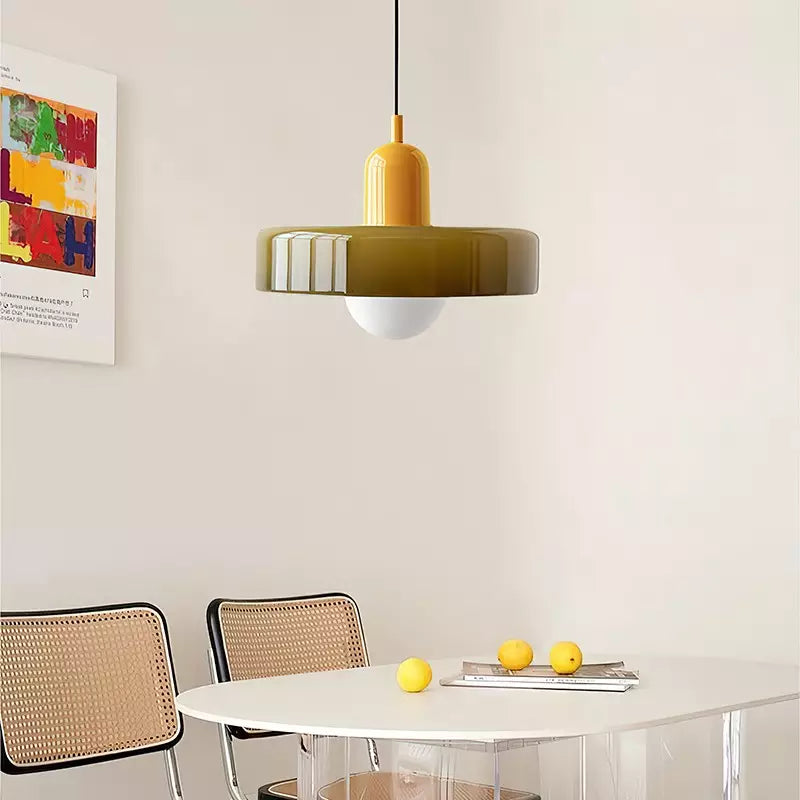 Gelbe Bauhaus Pendelleuchte aus Glas über weißem Tisch mit Stühlen, modernes Innendesign.