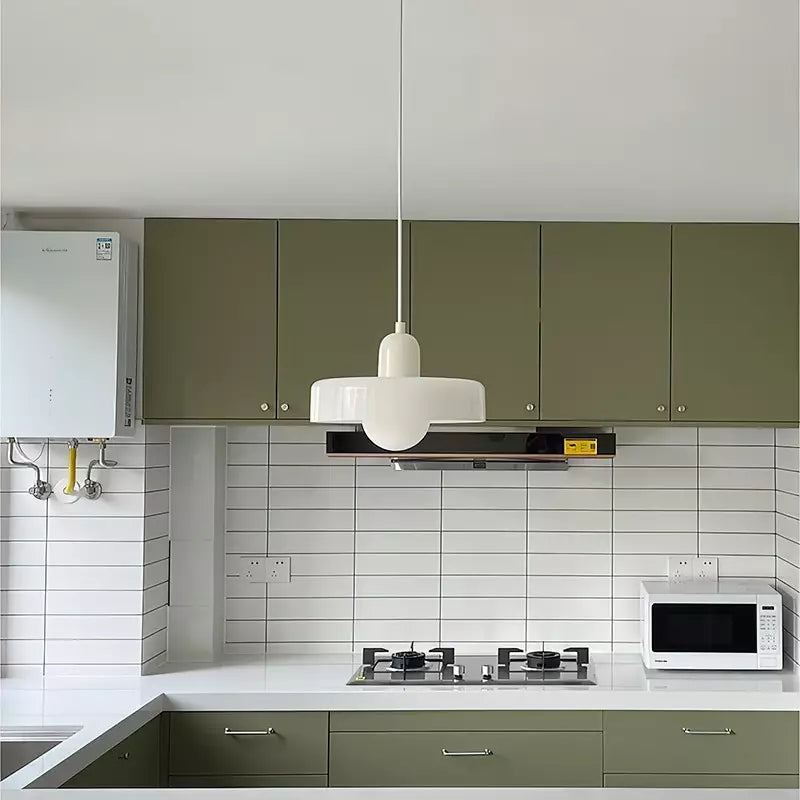 Moderne Küche mit weißem Hängelicht, grünen Schränken, Gasherd und Mikrowelle.