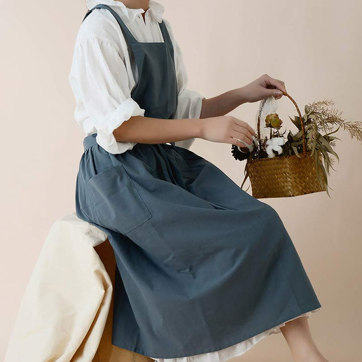 Frau in blauem Leinenkleid mit Korb, Blumen, weißer Bluse, minimalistischer Stil.