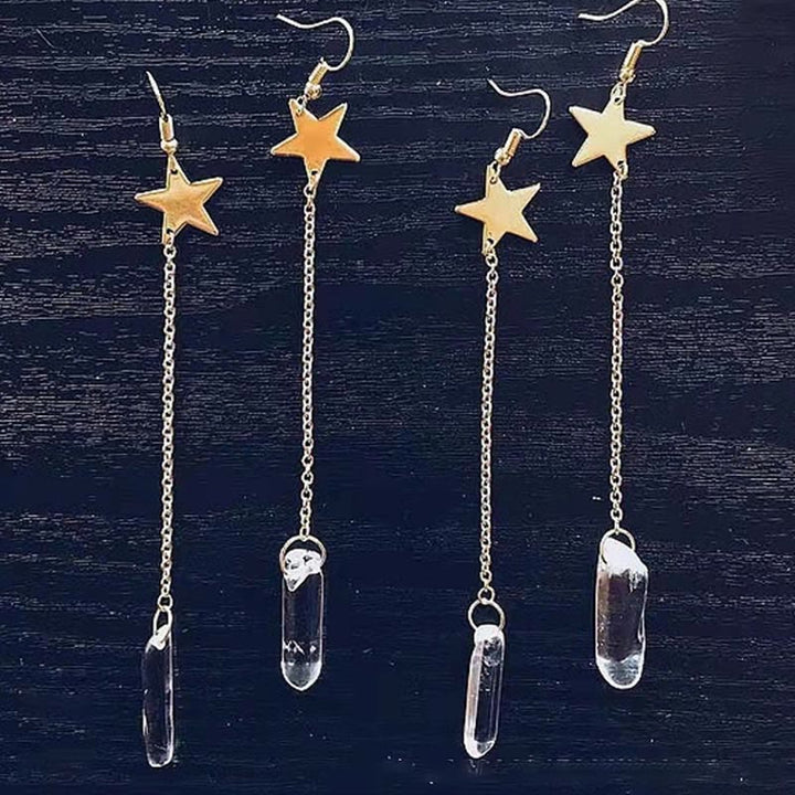 Goldene Stern-Ohrringe mit langen Ketten und klaren Kristallanhängern auf schwarzem Hintergrund.