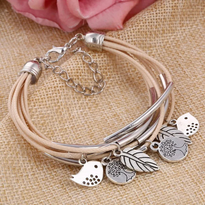 Beiges Lederarmband mit silbernen Anhängern, Blumen- und Vogelmotiven, Damenmode-Schmuck.