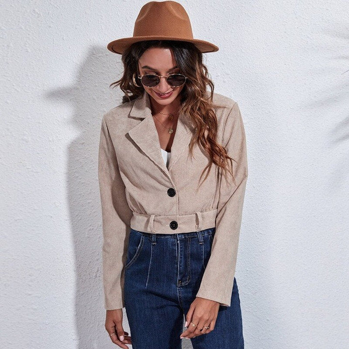 Frau in beigem Blazer und Jeans, trägt braunen Hut und Sonnenbrille, modischer Freizeitlook.