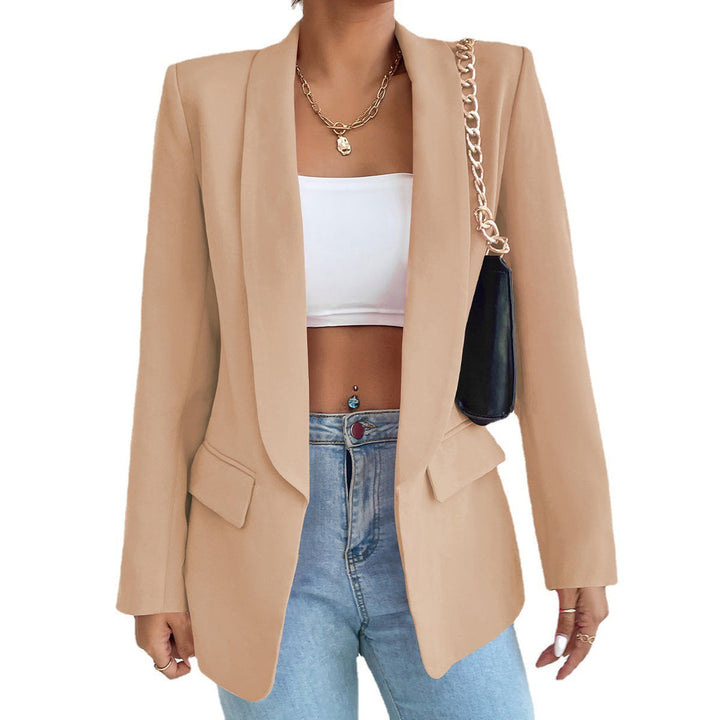 Frau in beigem Blazer, weißem Top, blauer Jeans, schwarze Tasche, goldene Kette.