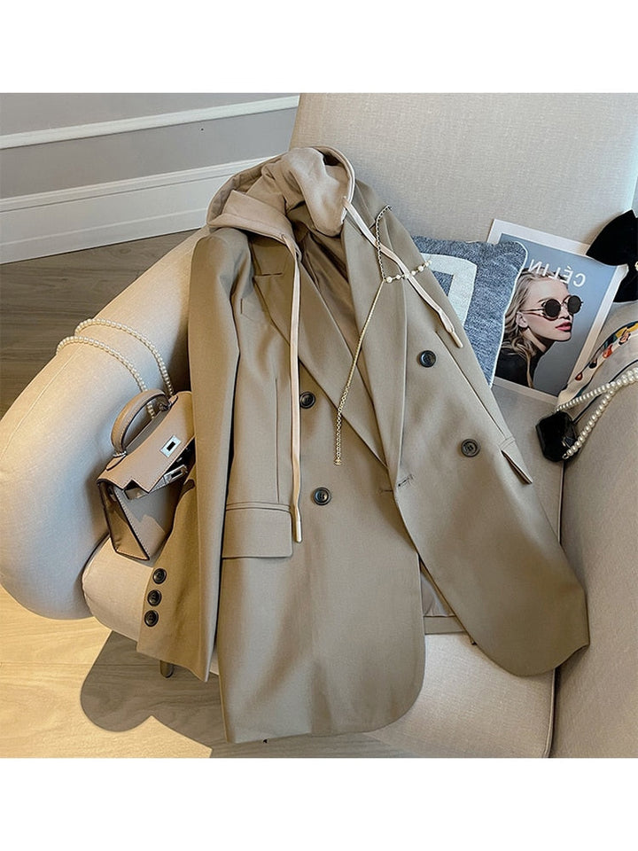 Beiger Damenblazer aus Wolle, elegant, mit Knöpfen, auf einem Sessel drapiert.