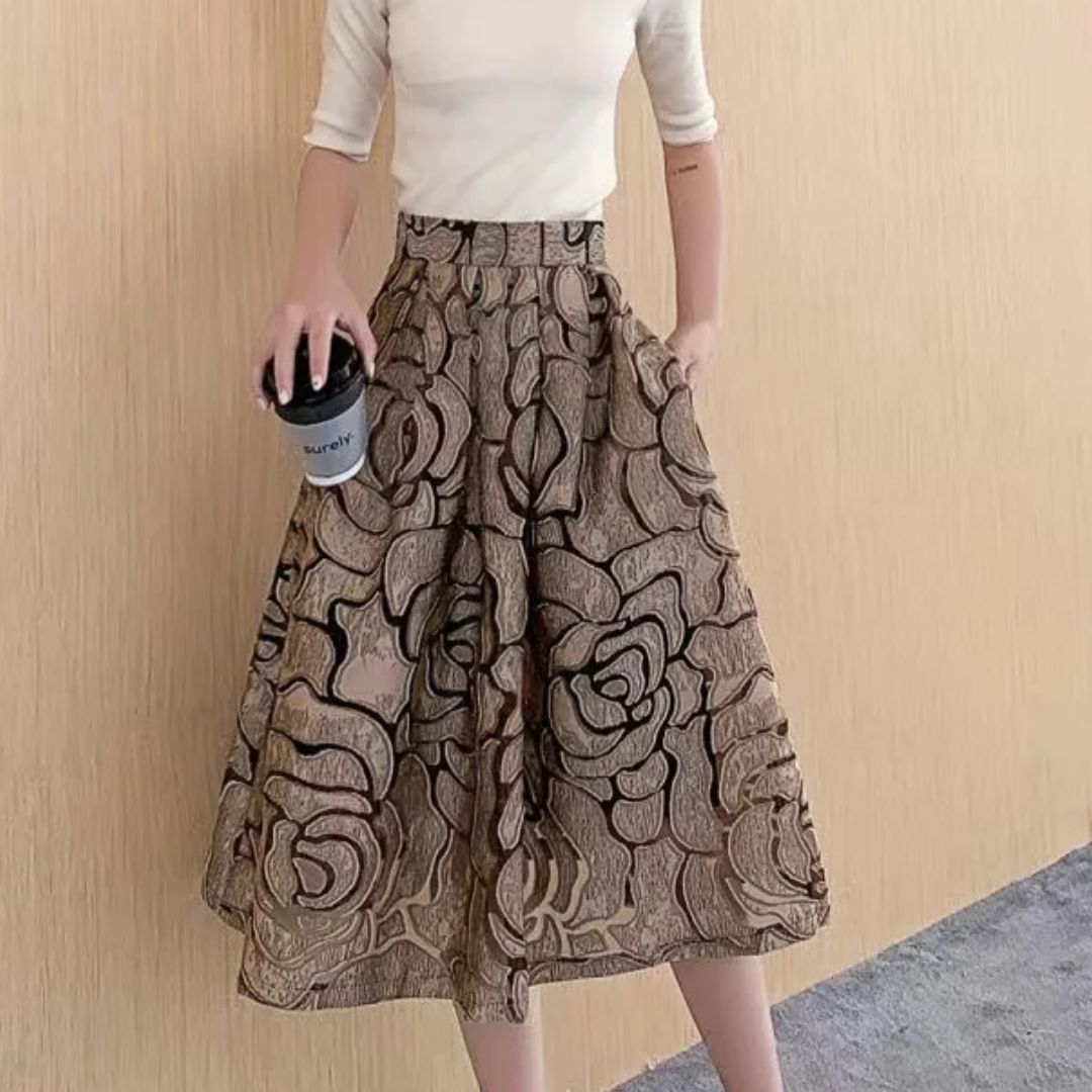 Frau in beigem Oberteil und geblümtem Rock hält Kaffeebecher, modisch, elegant, Freizeitkleidung.