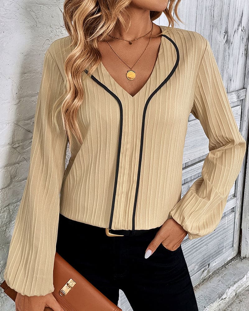 Beige Damenbluse mit V-Ausschnitt und schwarzen Akzenten, elegante Mode, langärmlig.