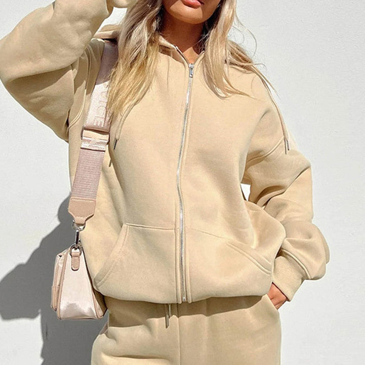 Frau in beigem Hoodie und Jogginghose, Umhängetasche, Freizeitmode, Streetwear-Look.