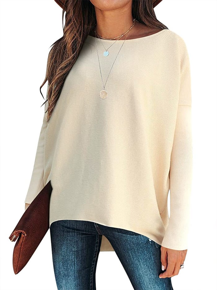 Frau in beigem Pullover, Jeans und Hut, hält braune Clutch, modisch, lässiger Look.