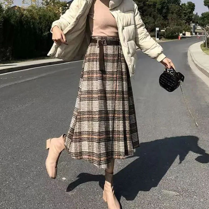 Frau in kariertem Rock, beiger Jacke und Stiefeletten auf Straße, modisch, Herbstmode.