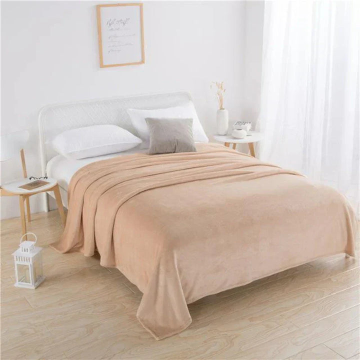 Beiges Plüschbettdecke auf weißem Bett, modernes Schlafzimmer, gemütliche Einrichtung.