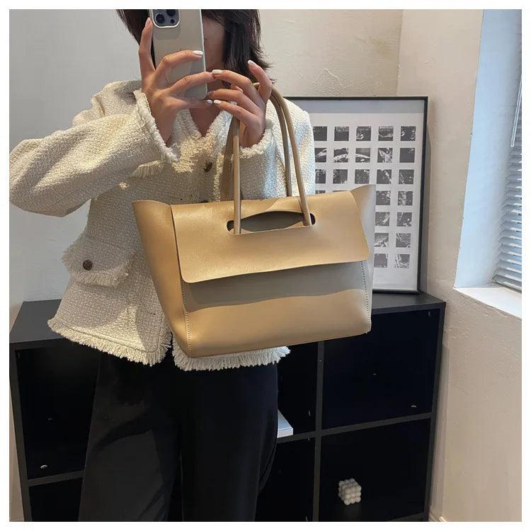 Frau mit beiger Ledertasche, Smartphone, weißer Jacke, modernes Interieur.