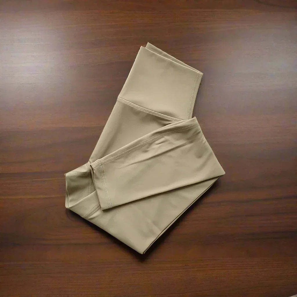 Beige Herrenhose aus Baumwolle, gefaltet auf Holztisch, elegante Freizeitmode.