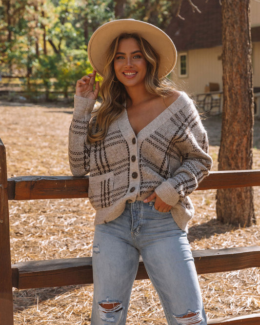 Frau in kariertem Strickcardigan und Jeans, lächelnd, mit Hut, im Freien, Herbstmode.