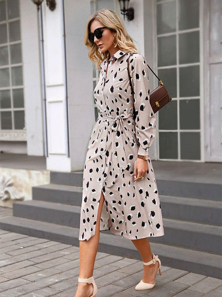Frau in beigem, gepunktetem Kleid, Sonnenbrille, braune Tasche, elegante Mode, Stadtstraße.