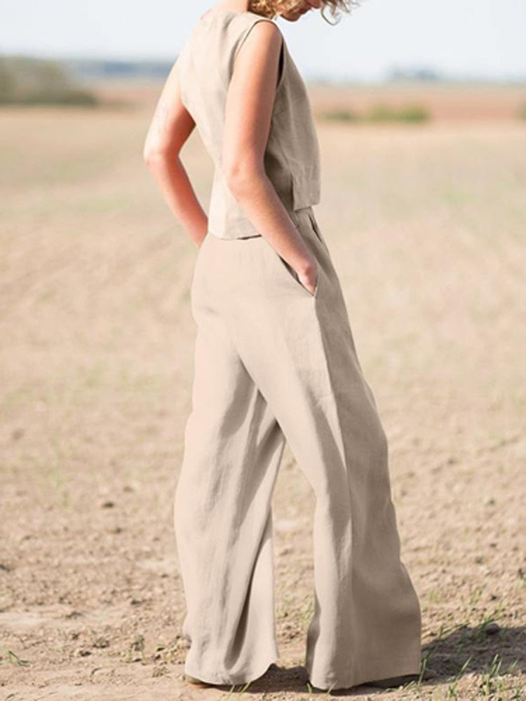 Frau in beigem Leinenanzug auf Feld, ärmelloses Top, weite Hose, Sommermode.