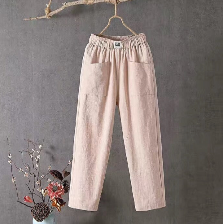 Beige Leinenhose mit elastischem Bund, Damenmode, lässig, bequem, hängend vor grauem Hintergrund.