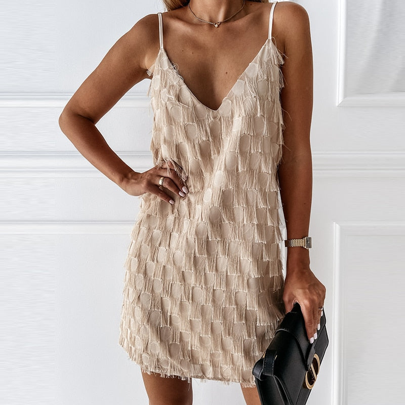 Frau in beige ärmellosem Minikleid mit V-Ausschnitt, hält schwarze Clutch, elegantes Outfit.