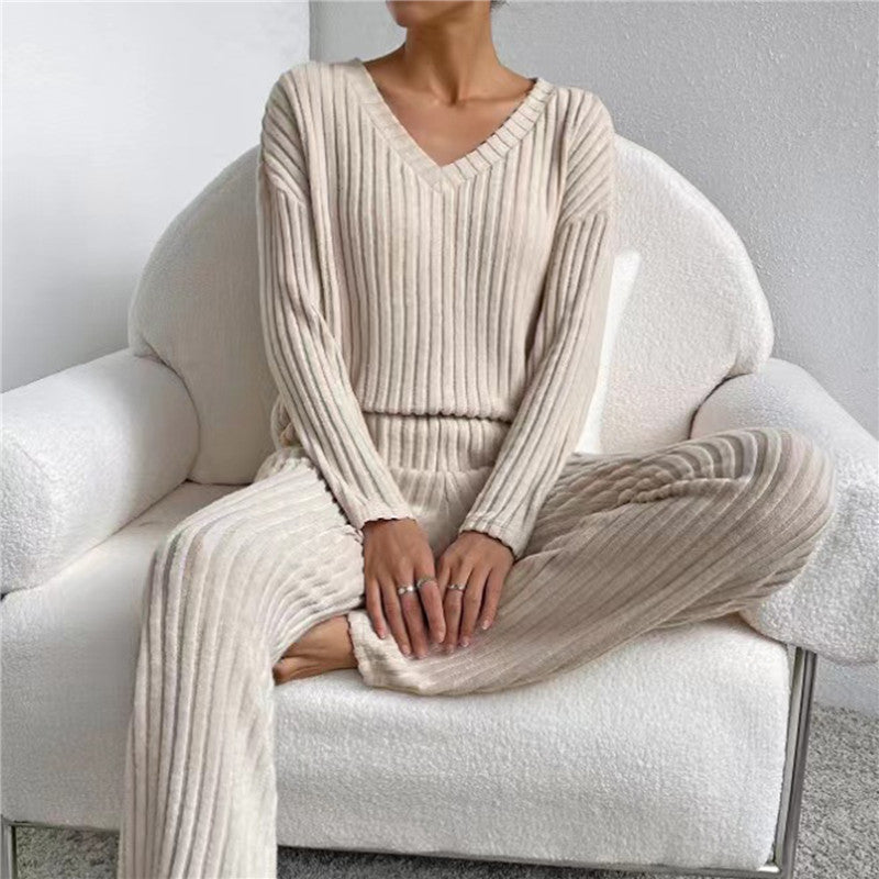 Frau in cremefarbenem Strickpullover und Hose auf weißem Sessel, gemütliche Damenmode.