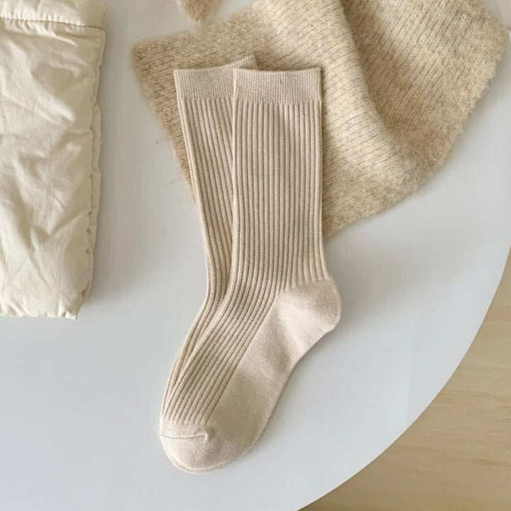 Beige Baumwollsocken auf weißem Tisch, gestrickte Textur, gemütliche Wintermode.