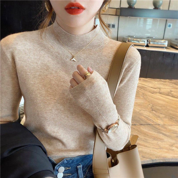 Frau in beigem Rollkragenpullover, goldene Halskette, rote Lippen, modisches Outfit.