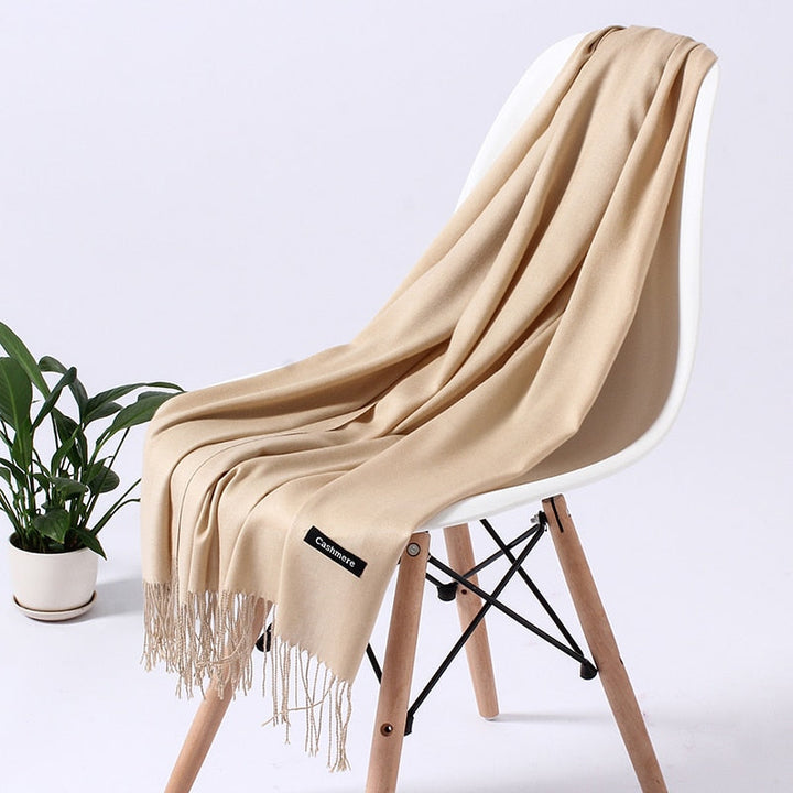 Beiger Kaschmirschal auf weißem Stuhl, weiches Material, Fransen, elegantes Design, Wohnzimmer.
