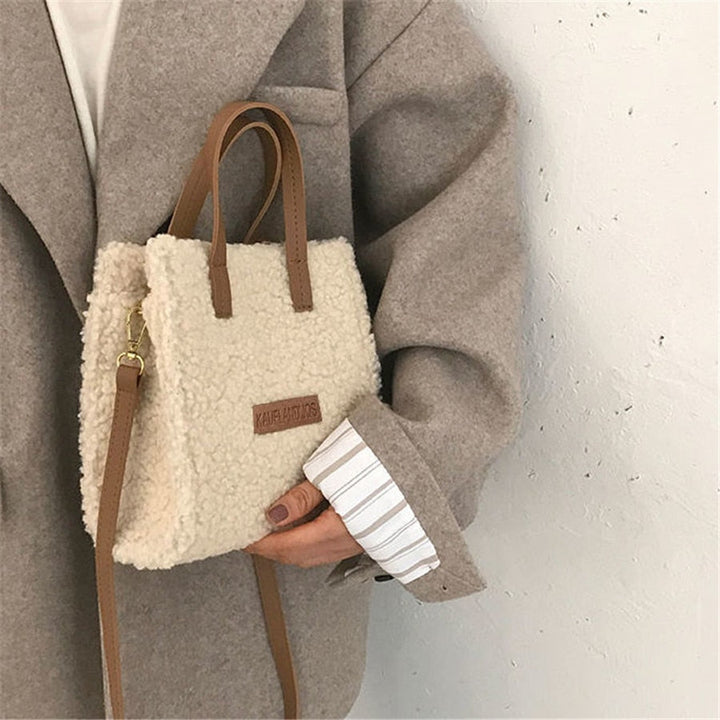 Damenhandtasche aus beigem Teddyfell mit braunen Ledergriffen, modisch und elegant.