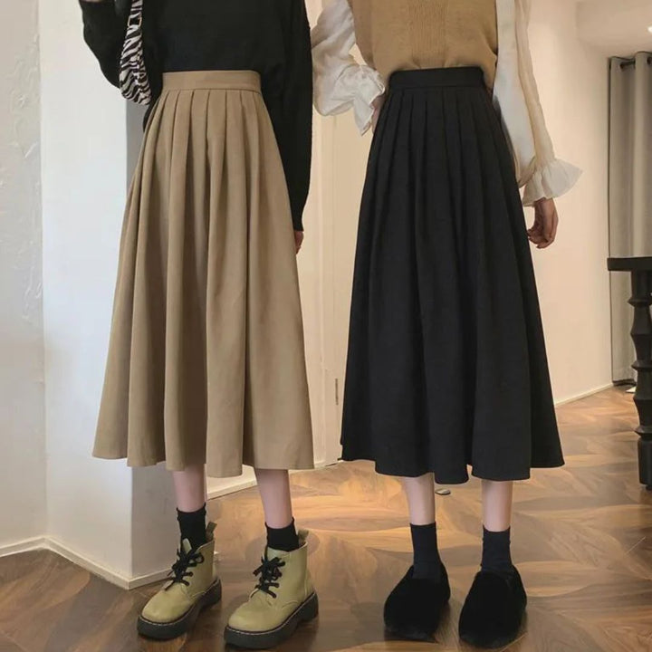 Zwei Frauen in langen Faltenröcken, beige und schwarz, modisch, Herbstmode, Innenraum.