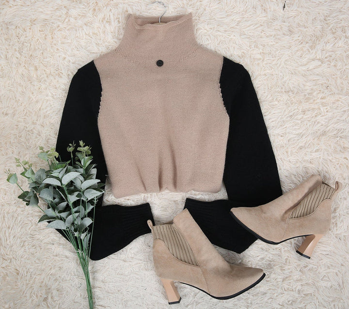 Beige Rollkragenpullover mit schwarzen Ärmeln, Stiefeletten, Kunstpflanze auf Teppich.