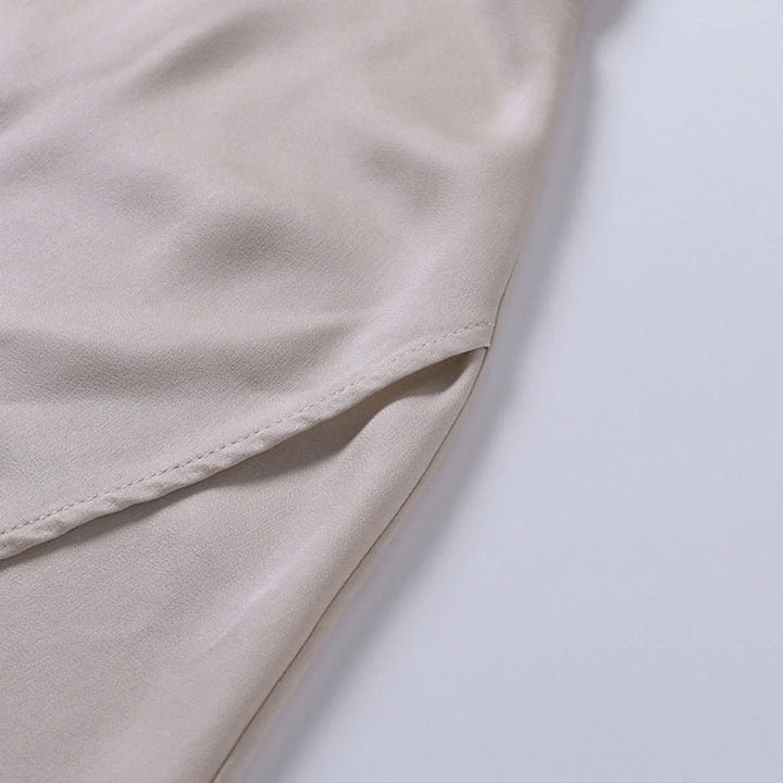 Beigefarbenes, langes Kleid aus Satin, Nahaufnahme, elegante Damenmode, weicher Stoff.